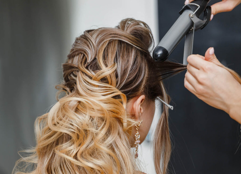 Closeup hairdresser coiffeur makes hairstyle.